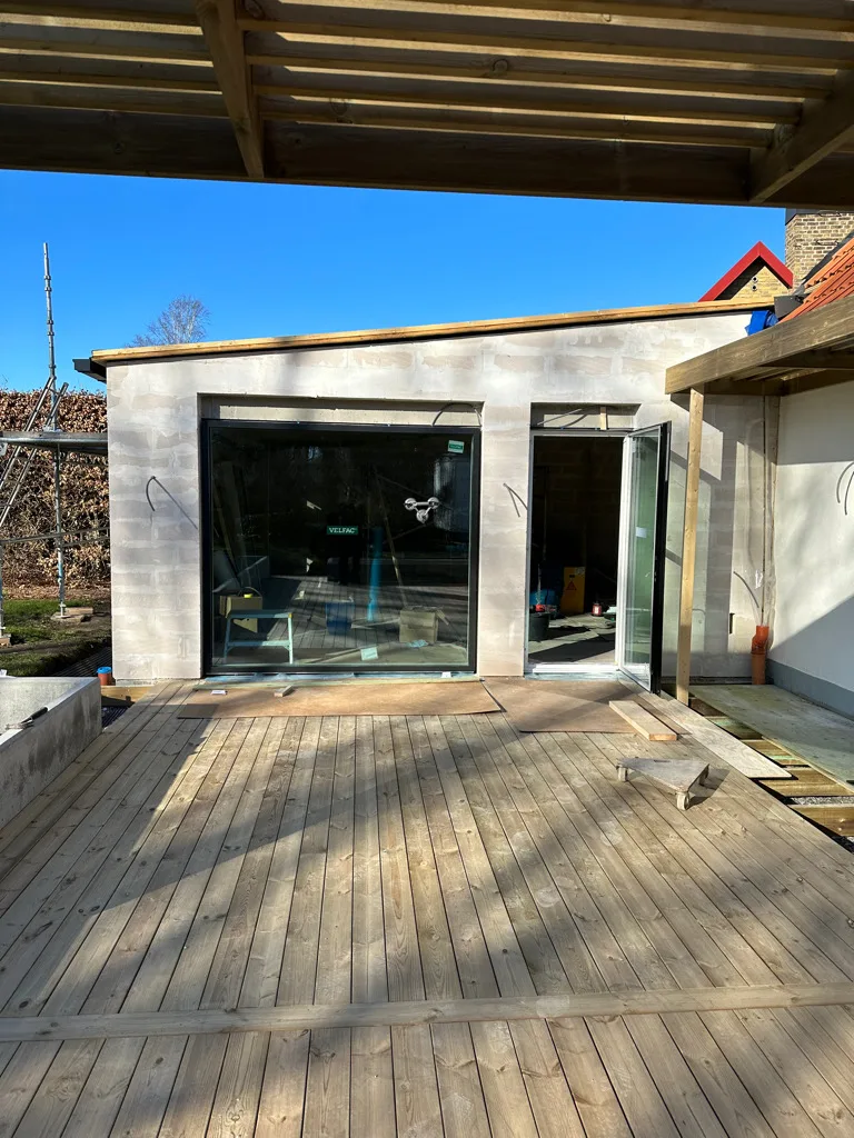 Tillbyggnad under uppförande med stort glasparti och nytt trädäck