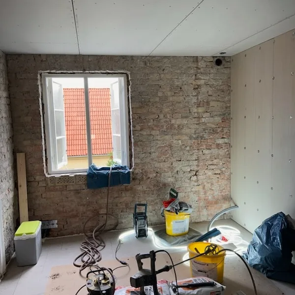 Rum under pågående renovering med tegelvägg och nytt gipstak