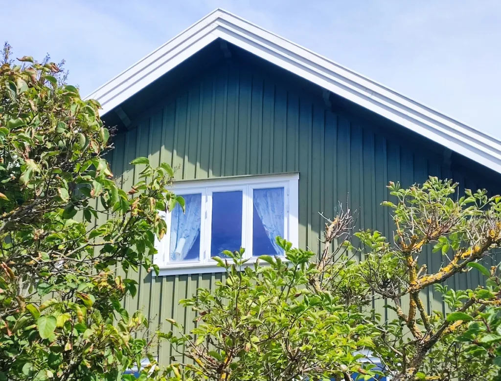 Grön träfasad på ett hus med vitt fönster