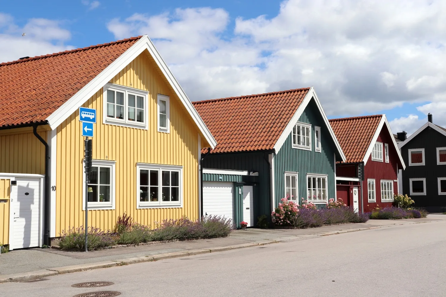 Tre färgglada hus med träfasader i gult, grönt och rött
