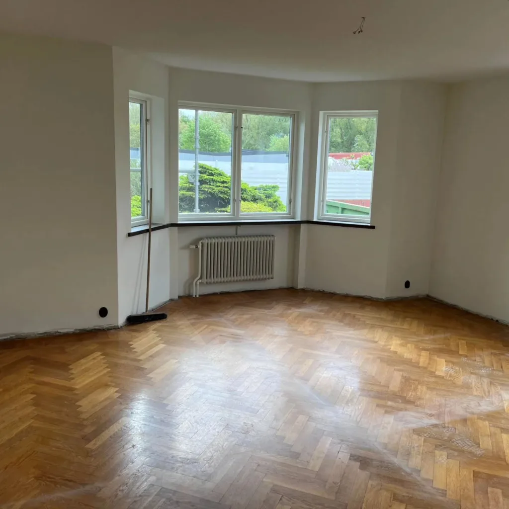 Rum under renovering med nyspacklade väggar och fiskbensparkett