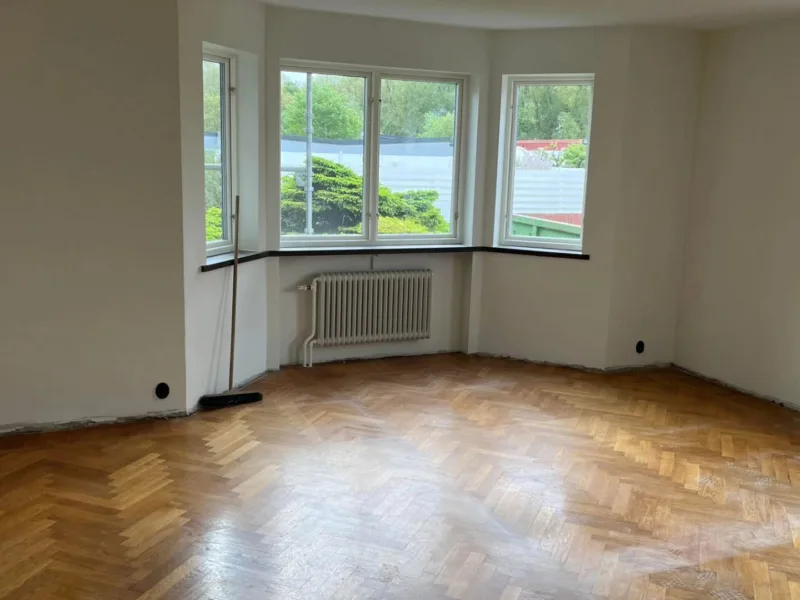 Rum under renovering med nyspacklade väggar och fiskbensparkett