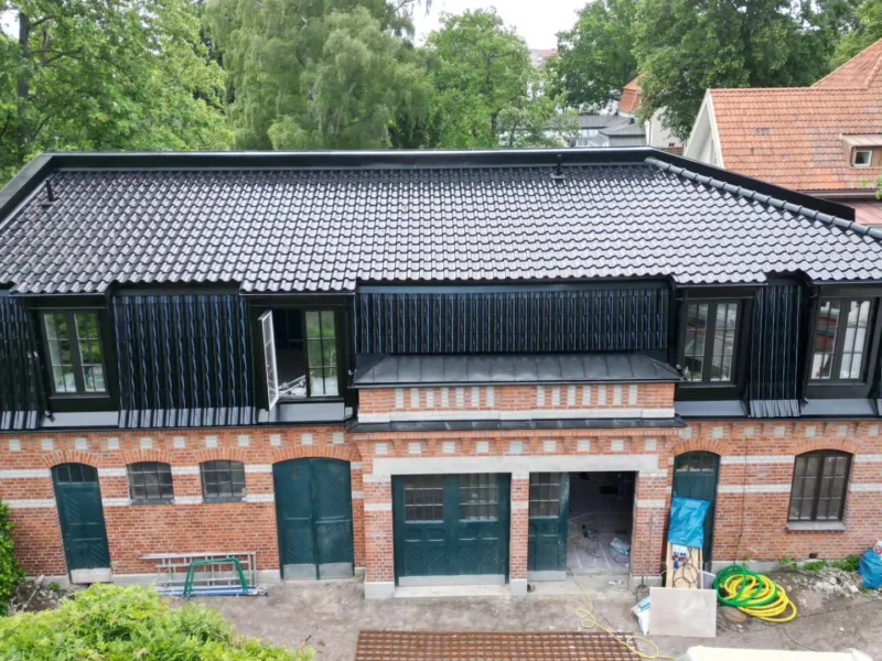 Tegelbyggnad med nytt svart tegeltak och takkupor