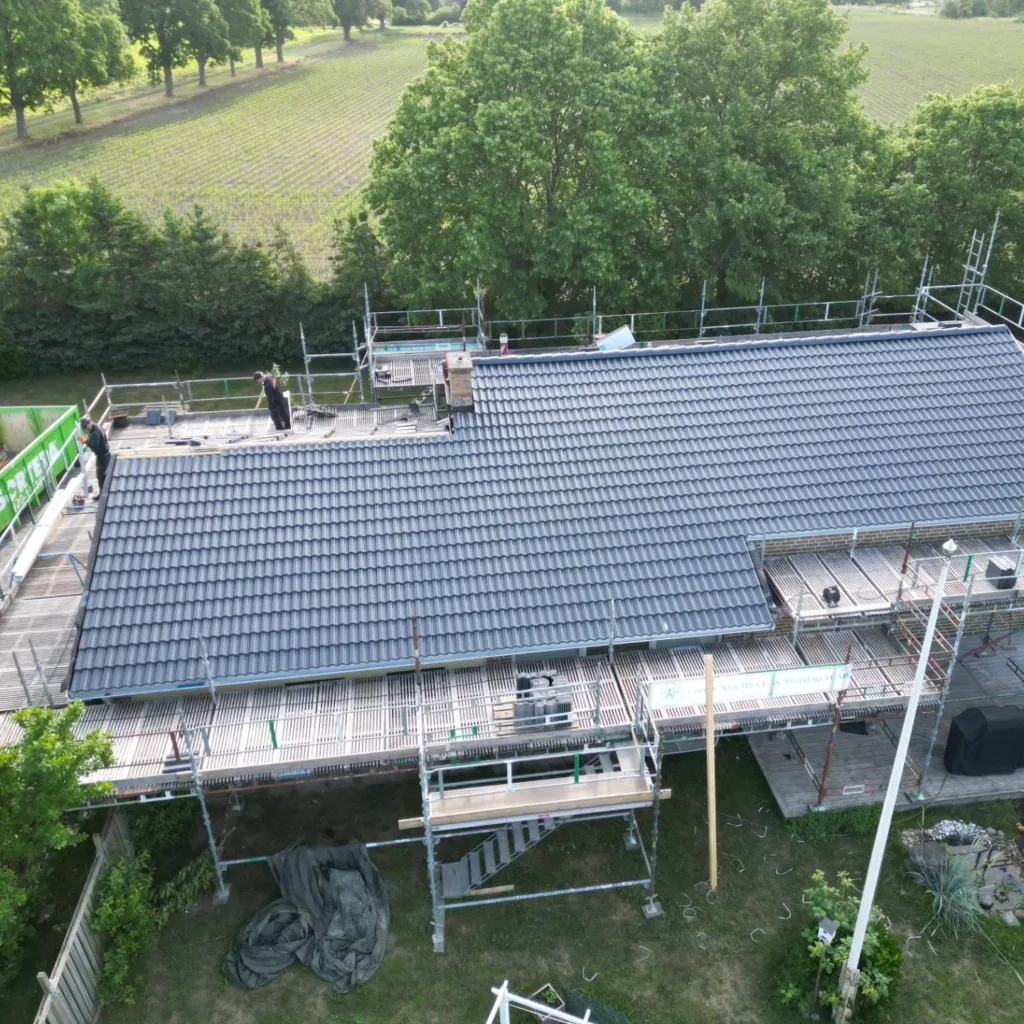 Takläggning pågår på villa, Herex hantverkare på taket
