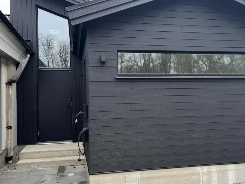 Tillbyggnad med svart liggande panel och ny entré