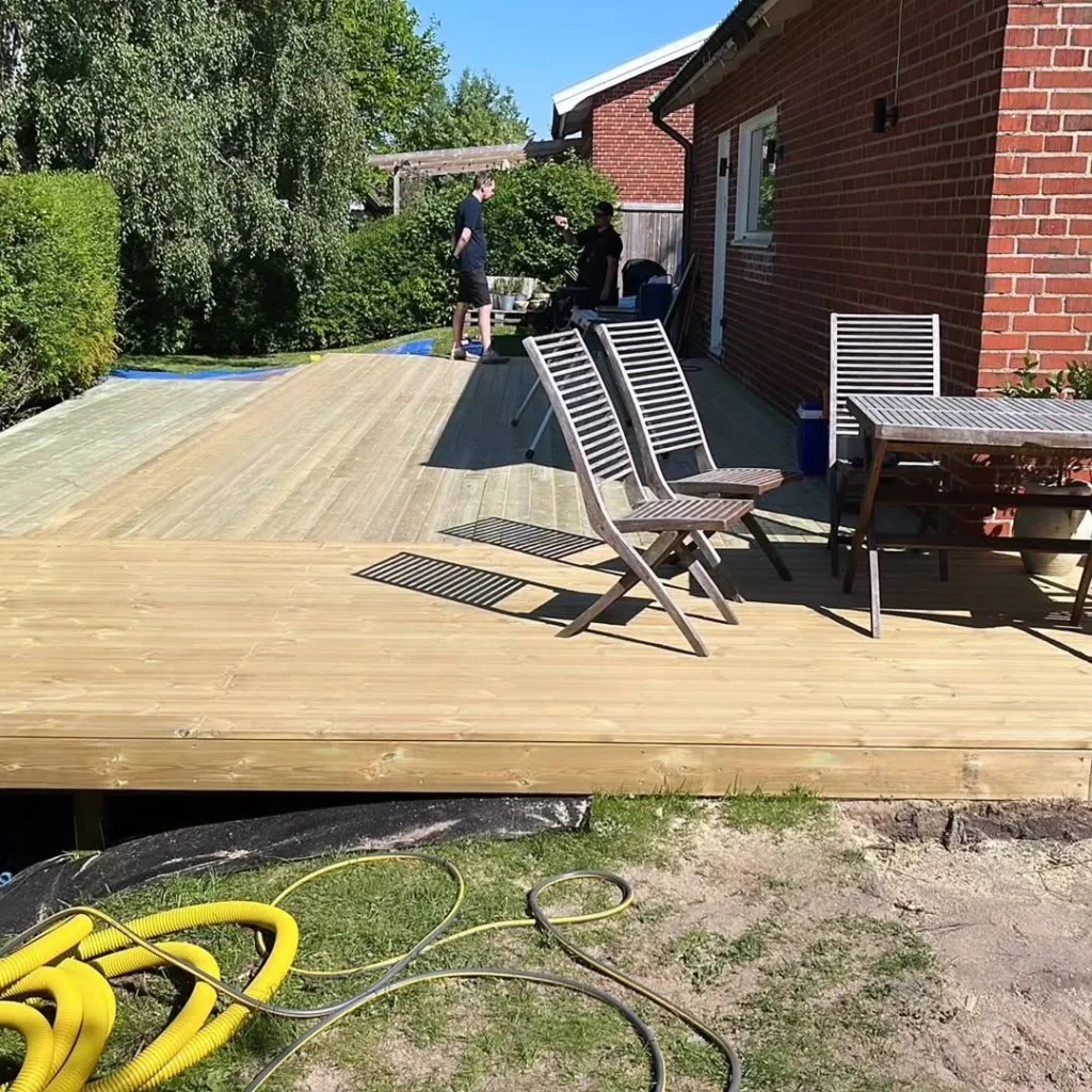 Stort trädäck vid tegelvilla med utemöbler