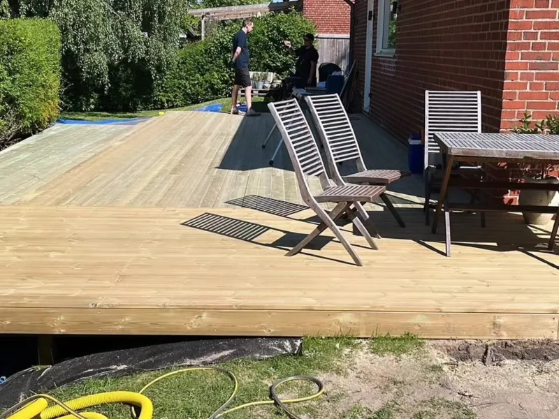 Stort trädäck vid tegelvilla med utemöbler
