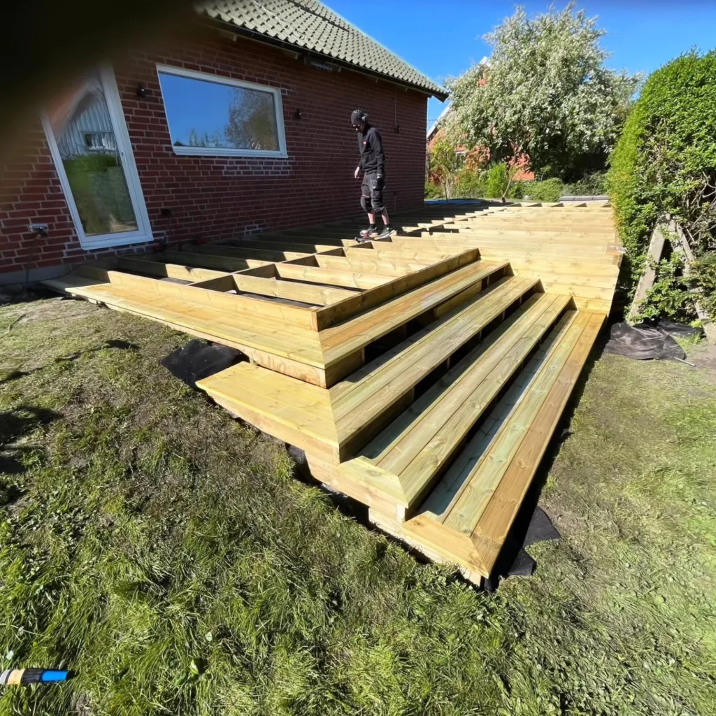 Trädäck med bred trappa ned mot gräsmattan
